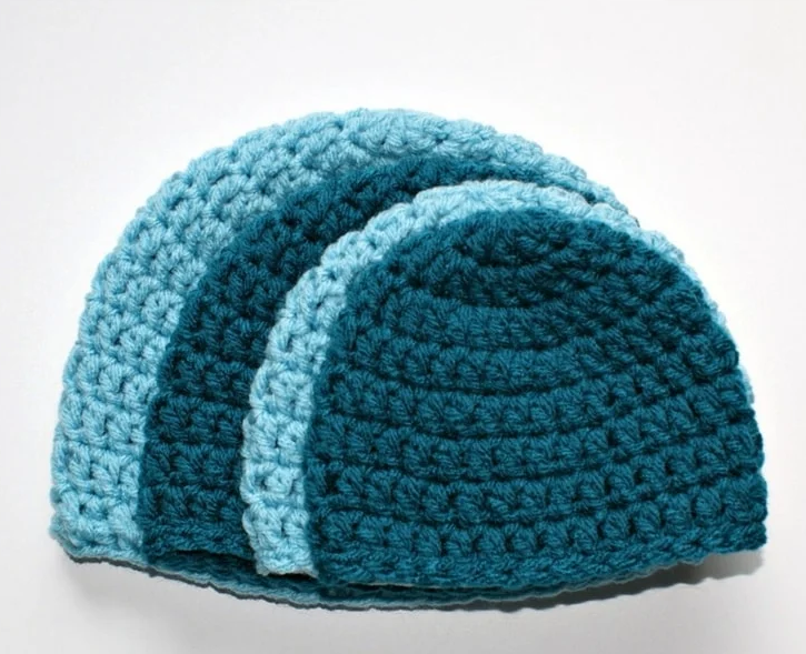 different sized crochet baby hats on top of each other